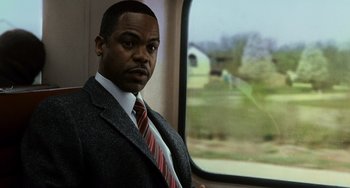 Movie still from “Source Code” (2011), directed by Duncan Jones – A man in a suit and tie on a train; Medium shot, Over the shoulder angle