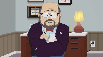 Movie still from “South Park: Joining the Panderverse” (2023), directed by Trey Parker – An animated man sitting at a desk in front of a lamp; Medium shot, Over the shoulder angle