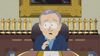 Movie still from “South Park: Joining the Panderverse” (2023), directed by Trey Parker – An old man sitting at a table in front of an award; Medium shot, High angle