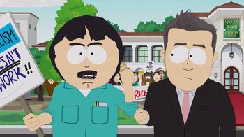 Movie still from “South Park: Joining the Panderverse” (2023), directed by Trey Parker – Two men standing next to each other in front of a crowd; Medium shot, Over the shoulder angle