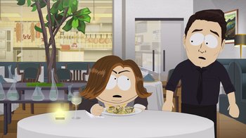 Movie still from “South Park: Joining the Panderverse” (2023), directed by Trey Parker – A woman sitting at a table with a plate of food in front of her; Medium shot, Over the shoulder angle
