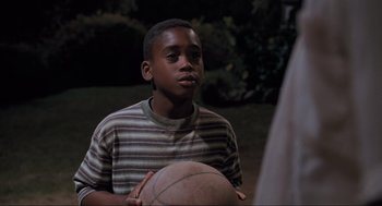 Movie still from “Space Jam” (1996), directed by Joe Pytka – A young boy holding a basketball in his hands; Medium shot, High angle