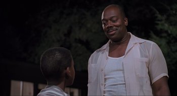 Movie still from “Space Jam” (1996), directed by Joe Pytka – A man standing next to a boy in a white shirt; Medium shot, Low angle