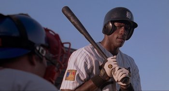 Movie still from “Space Jam” (1996), directed by Joe Pytka – A baseball player holding a baseball bat on top of a baseball field; Close Up shot, Over the shoulder angle