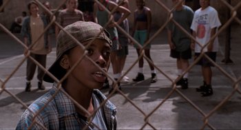 Movie still from “Space Jam” (1996), directed by Joe Pytka – A young man looking through a chain link fence; Close Up shot, High angle