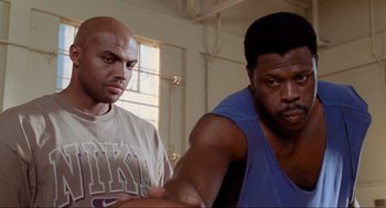 Movie still from “Space Jam” (1996), directed by Joe Pytka – Two men are standing in front of a window; Close Up shot, Low angle