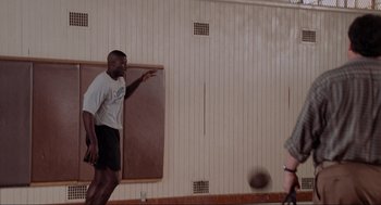 Movie still from “Space Jam” (1996), directed by Joe Pytka – A man in white shirt and black shorts throwing a basketball; Wide shot, Over the shoulder angle