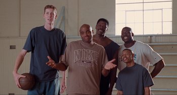 Movie still from “Space Jam” (1996), directed by Joe Pytka – A group of men standing next to each other in front of a window; Medium shot, Low angle