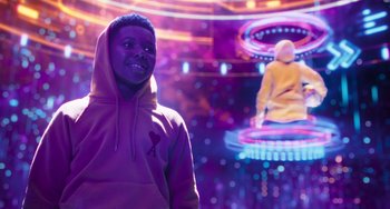 Movie still from “Space Jam: A New Legacy” (2021), directed by Malcolm D. Lee – A man in a purple hoodie standing in front of neon lights; Medium shot, Over the shoulder angle