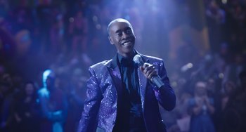Movie still from “Space Jam: A New Legacy” (2021), directed by Malcolm D. Lee – A man in a purple jacket is holding a microphone; Medium shot, Low angle