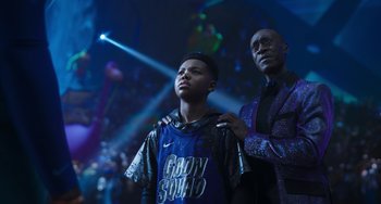 Movie still from “Space Jam: A New Legacy” (2021), directed by Malcolm D. Lee – A man standing next to a young boy in front of lights; Medium shot, Low angle