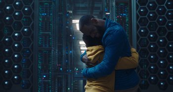 Movie still from “Space Jam: A New Legacy” (2021), directed by Malcolm D. Lee – A man and a woman hugging in a room; Extreme Wide shot, Low angle