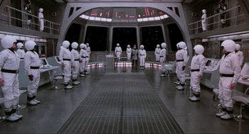 Movie still from “Spaceballs” (1987), directed by Mel Brooks – A group of people in white suits standing in a room; Extreme Wide shot, High angle