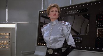 Movie still from “Spaceballs” (1987), directed by Mel Brooks – A woman wearing a silver shirt and black pants; Medium shot, Low angle