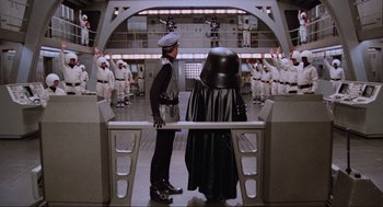 Movie still from “Spaceballs” (1987), directed by Mel Brooks – Two people in a room with a crowd of people; Wide shot, High angle