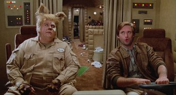 Movie still from “Spaceballs” (1987), directed by Mel Brooks – Two men sitting in a living room next to each other; Medium shot, Over the shoulder angle