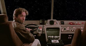 Movie still from “Spaceballs” (1987), directed by Mel Brooks – A man sitting at the steering wheel of a car in front of a computer; Medium shot, Over the shoulder angle