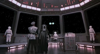 Movie still from “Spaceballs” (1987), directed by Mel Brooks – A scene of a star wars movie with darth vadar and luke skywalker; Wide shot, Over the shoulder angle