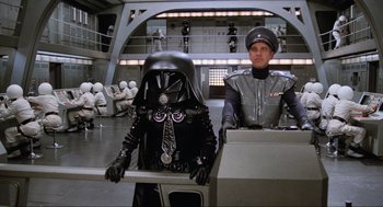 Movie still from “Spaceballs” (1987), directed by Mel Brooks – Two people in costumes sitting in a space station; Wide shot, High angle