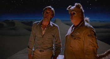 Movie still from “Spaceballs” (1987), directed by Mel Brooks – Two men standing next to each other in a desert; Medium shot, Low angle