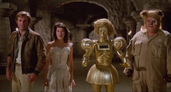 Movie still from “Spaceballs” (1987), directed by Mel Brooks – A woman in a white dress standing next to a gold robot; Wide shot, Low angle