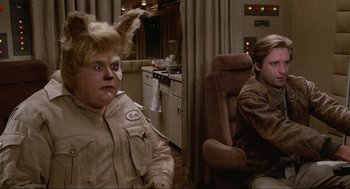 Movie still from “Spaceballs” (1987), directed by Mel Brooks – A man with a bunny ears sitting next to another man with a bunny ears; Medium shot, Over the shoulder angle