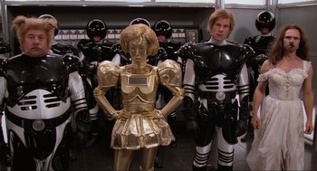 Movie still from “Spaceballs” (1987), directed by Mel Brooks – A group of people dressed in black and gold costumes; Wide shot, High angle