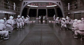Movie still from “Spaceballs” (1987), directed by Mel Brooks – A group of people dressed in white are sitting in a room; Extreme Wide shot, High angle