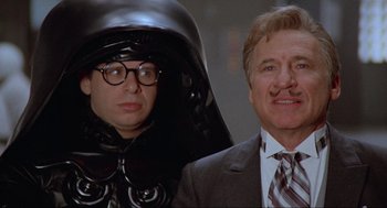 Movie still from “Spaceballs” (1987), directed by Mel Brooks – A man in a suit and tie standing next to another man in a suit and tie; Close Up shot, Over the shoulder angle