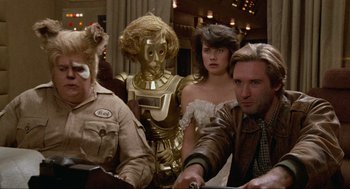 Movie still from “Spaceballs” (1987), directed by Mel Brooks – A group of people sitting at a table with a robot; Medium shot, Over the shoulder angle