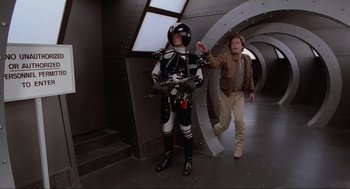 Movie still from “Spaceballs” (1987), directed by Mel Brooks – A man and a woman are standing next to each other in a tunnel; Wide shot, High angle