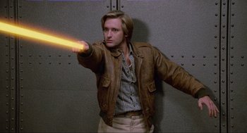 Movie still from “Spaceballs” (1987), directed by Mel Brooks – A man in a brown jacket holding a yellow object; Medium shot, Low angle