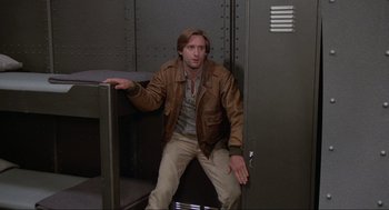 Movie still from “Spaceballs” (1987), directed by Mel Brooks – A man sitting on top of a chair in a room; Medium shot, Low angle