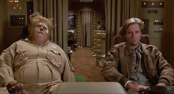 Movie still from “Spaceballs” (1987), directed by Mel Brooks – Two people sitting in a living room next to each other; Medium shot, Low angle