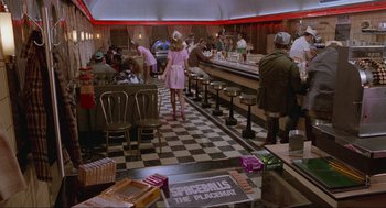 Movie still from “Spaceballs” (1987), directed by Mel Brooks – People are sitting at a restaurant with tables , chairs and booths; Wide shot, Over the shoulder angle