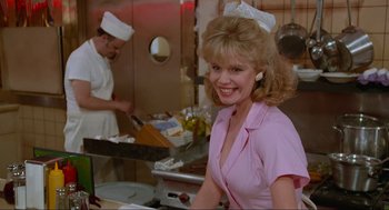 Movie still from “Spaceballs” (1987), directed by Mel Brooks – A woman wearing a pink shirt and a white hat in a kitchen; Medium shot, Low angle