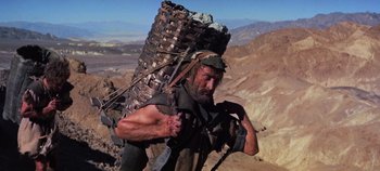 Movie still from “Spartacus” (1960), directed by Stanley Kubrick – A man carrying a large basket on his back; Wide shot, Low angle