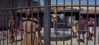 Movie still from “Spartacus” (1960), directed by Stanley Kubrick – A man standing in front of an iron gate; Wide shot, High angle