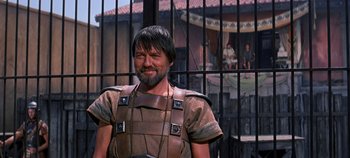 Movie still from “Spartacus” (1960), directed by Stanley Kubrick – A man in a roman outfit standing in front of an iron gate; Medium shot, Over the shoulder angle