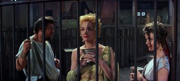 Movie still from “Spartacus” (1960), directed by Stanley Kubrick – A woman holding a cell phone standing next to a fence; Medium shot, Over the shoulder angle