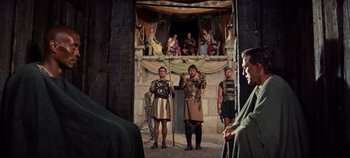 Movie still from “Spartacus” (1960), directed by Stanley Kubrick – A group of men standing next to each other in roman clothing; Wide shot, Over the shoulder angle