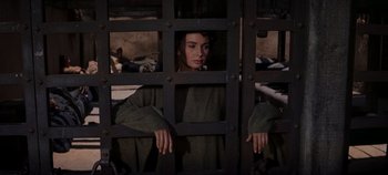 Movie still from “Spartacus” (1960), directed by Stanley Kubrick – A woman standing behind bars in a jail cell; Medium shot, High angle