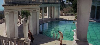 Movie still from “Spartacus” (1960), directed by Stanley Kubrick – A man and a woman are standing in front of a swimming pool; Extreme Wide shot, High angle