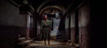 Movie still from “Spartacus” (1960), directed by Stanley Kubrick – A man dressed as a roman soldier stands in an abandoned building; Wide shot, Low angle