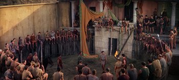 Movie still from “Spartacus” (1960), directed by Stanley Kubrick – A group of people in a courtyard with a fire pit; Extreme Wide shot, High angle