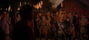 Movie still from “Spartacus” (1960), directed by Stanley Kubrick – A group of people standing in front of a crowd of people; Medium shot, Over the shoulder angle