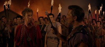 Movie still from “Spartacus” (1960), directed by Stanley Kubrick – A group of people in a room with fire; Medium shot, Over the shoulder angle