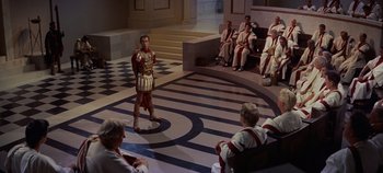 Movie still from “Spartacus” (1960), directed by Stanley Kubrick – A man dressed as a roman soldier stands in front of a group of people; Extreme Wide shot, High angle
