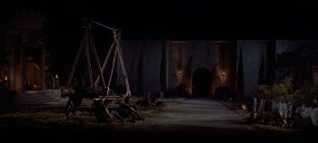 Movie still from “Spartacus” (1960), directed by Stanley Kubrick – A group of people sitting on the ground in front of a building; Extreme Wide shot, High angle
