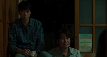 Movie still from “Broker” (2022), directed by Kore-eda Hirokazu – A man and a woman sitting next to each other in a room; Medium shot, Over the shoulder angle